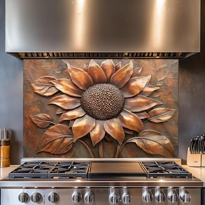 Puede incluir: Un protector contra salpicaduras de cocina con forma de girasol de color cobre, con pétalos y hojas detallados. El girasol está montado sobre una estufa de gas de acero inoxidable. La decoración de la cocina tiene un tema rústico inspirado en la naturaleza.