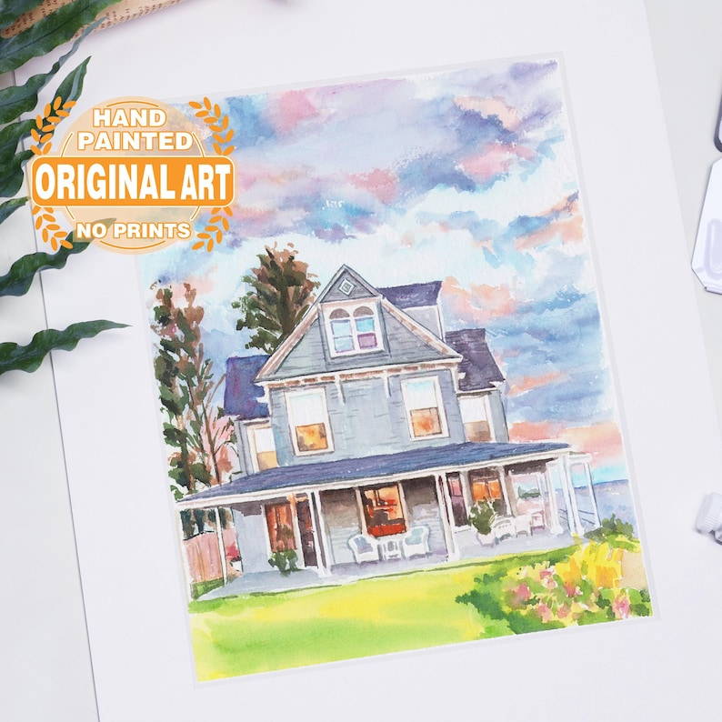 May include: Watercolor painting of a two-story house with a porch, set against a sunset sky. The house is painted in shades of blue and gray, with a green lawn and colorful flowers in the foreground. Text on the image reads "HAND PAINTED ORIGINAL ART NO PRINTS."