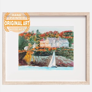 May include: Hand-painted original art print of a coastal scene. The watercolor painting depicts houses on a cliff overlooking the water, with a sailboat in the foreground. The artwork is framed in a light wood frame. The text on the image says "Hand Painted Original Art No Prints".