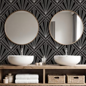 Pode incluir: Uma bancada de casa de banho com dois espelhos redondos, lavatórios brancos e uma prateleira de madeira. O papel de parede apresenta um design art déco preto e cinzento. A prateleira contém toalhas, cestos e objetos decorativos.