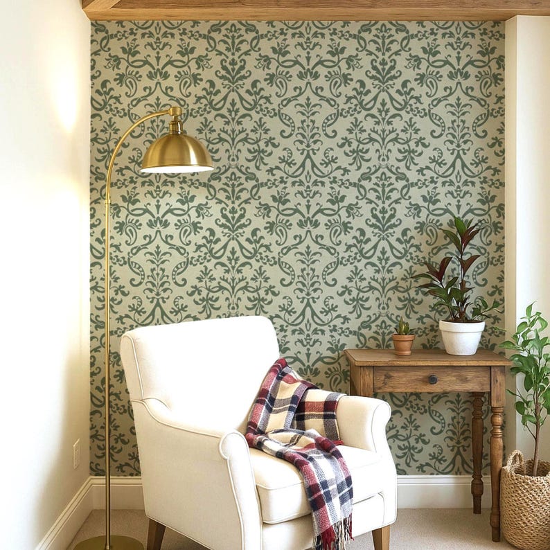 a cozy living room with a white armchair, a wooden side table, and a floor lamp. The wall behind the armchair has a decorative green and white pattern, and there are two potted plants in the room.