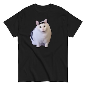 May include: Black t-shirt featuring a white cat with black markings. The cat has a surprised expression. The t-shirt is made of a soft material and is suitable for casual wear.