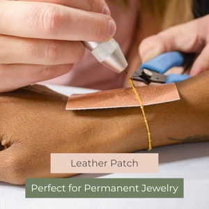 May include: A person's wrist with a small, brown leather patch and a gold chain attached to it. The chain is being secured with a tool. The text "Leather Patch" and "Perfect for Permanent Jewelry" is visible below the image.