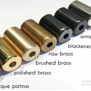 May include: A collection of cylindrical metal objects in various finishes, including polished chrome, antique black, and polished brass. The objects are arranged in a row, showcasing different colors and textures. Text labels identify each finish.