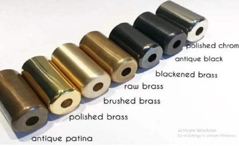 May include: A collection of cylindrical metal objects in various finishes, including polished chrome, antique black, and polished brass. The objects are arranged in a row, showcasing different colors and textures. Text labels identify each finish.
