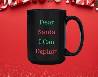 May include: Black coffee mug with white text that reads "Dear Santa I Can Explain". The text is in green and red.