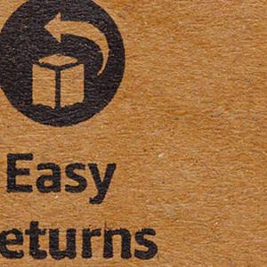 May include: Close-up of a brown cardboard surface with the words "Easy Returns" printed in black. Above the text is a black circular symbol with a box and an arrow, indicating returns.