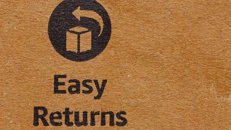May include: Close-up of a brown cardboard surface with the words "Easy Returns" printed in black. Above the text is a black circular symbol with a box and an arrow, indicating returns.