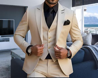 May include: A beige three-piece suit with a black vest and a black tie. The suit jacket has a notch lapel and a single button closure. The vest has a five-button closure and the tie is a solid black.