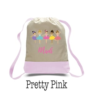 May include: A light pink drawstring bag with a beige canvas top. The bag features a design of five ballerinas in colorful tutus and the name "Madi" in pink lettering. The bag is labeled "Pretty Pink".