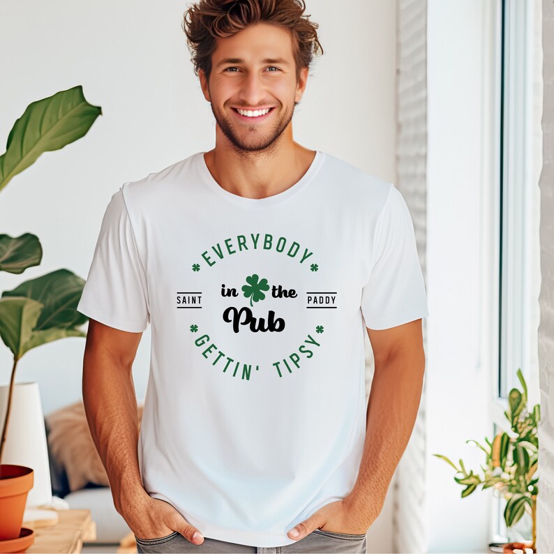 Puede incluir: Camiseta blanca con un tr&eacute;bol verde y el texto "Everybody in the Pub Gettin' Tipsy" en un c&iacute;rculo negro.