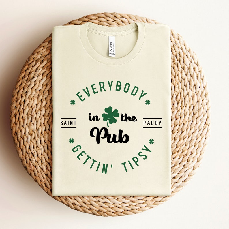Puede incluir: Una camiseta verde claro con un gr&aacute;fico negro y verde que dice "Everybody in the Pub Gettin' Tipsy" con un dise&ntilde;o de tr&eacute;bol.