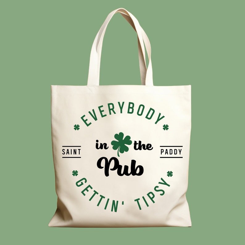 Puede incluir: Una bolsa de lona blanca con un tr&eacute;bol verde y el texto "Everybody in the Pub Gettin' Tipsy" en un c&iacute;rculo.