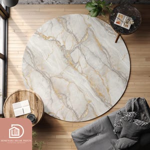 May include: A round area rug with a marble design. The rug features a white background with gray and gold veining. The rug is placed on a wooden floor, with a sofa and side tables visible in the background. The rug's diameter is approximately 7 feet.