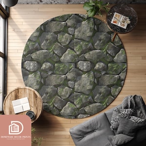 May include: A circular rug with a stone wall design. The rug displays a pattern of grey stones with green moss. It's placed on a wooden floor, with a sofa and small tables nearby. The rug's diameter is approximately 150 cm.