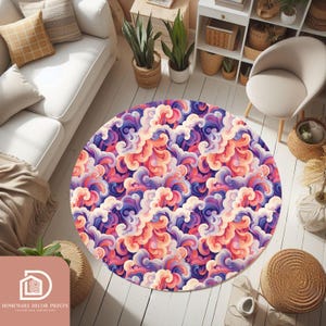 Pode incluir: Um tapete redondo com um padrão colorido e rodopiante em tons de roxo, rosa, laranja e creme. O tapete, colocado sobre um chão branco, apresenta um padrão abstrato de nuvens ou ondas. Um elemento de decoração para casa.