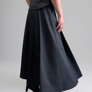 May include: A black, knee-length skirt with a wide, flowing silhouette. The skirt has a high waist and a slightly flared hem.