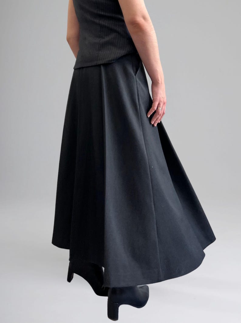 May include: A black, knee-length skirt with a wide, flowing silhouette. The skirt has a high waist and a slightly flared hem.