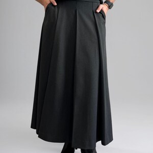 May include: A black pleated skirt with pockets. The skirt is knee-length and has a straight silhouette.