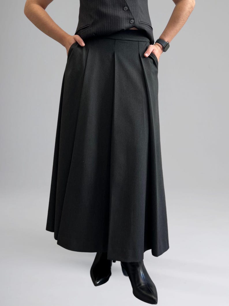 May include: A black pleated skirt with pockets. The skirt is knee-length and has a straight silhouette.