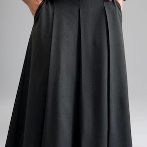 May include: A black pleated skirt with a high waist and a straight, flowing silhouette.