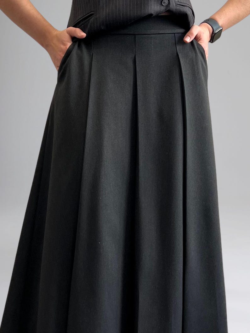 May include: A black pleated skirt with a high waist and a straight, flowing silhouette.