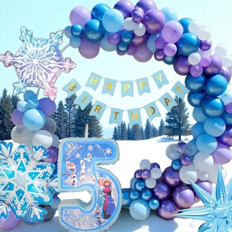 Puede incluir: Una escena de fiesta de cumplea&ntilde;os con un arco de globos azules y morados, decoraciones de copos de nieve y una pancarta que dice "Happy Birthday". Un gran globo con el n&uacute;mero 5 presenta personajes de la pel&iacute;cula Frozen.