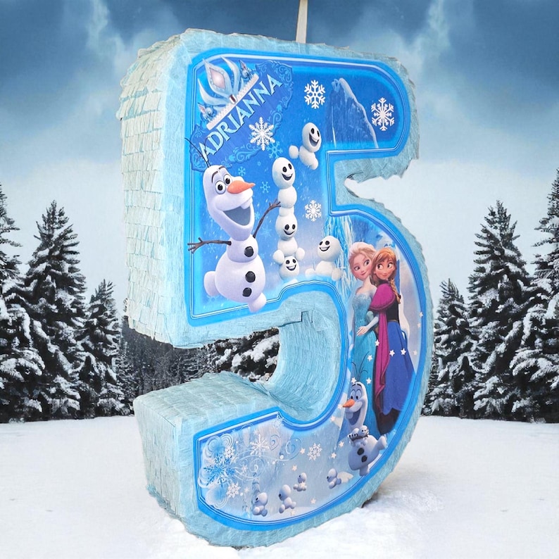 Puede incluir: Una pi&ntilde;ata grande, de color azul claro, con el n&uacute;mero 5 y tem&aacute;tica invernal. La pi&ntilde;ata presenta personajes de la pel&iacute;cula Frozen, como Olaf, Anna y Elsa. El nombre "Adrianna" est&aacute; impreso en la parte delantera. La pi&ntilde;ata est&aacute; decorada con copos de nieve y mu&ntilde;ecos de nieve.