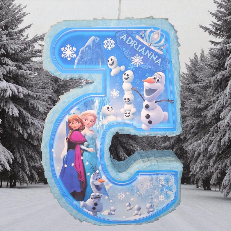 Puede incluir: Una pi&ntilde;ata con el n&uacute;mero 5 con personajes de la pel&iacute;cula Frozen, incluyendo a Anna, Elsa y Olaf. La pi&ntilde;ata es azul y blanca con el nombre "Adrianna" y est&aacute; decorada con copos de nieve y mu&ntilde;ecos de nieve.