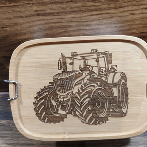 Könnte beinhalten: Eine Holzlunchbox mit einem lasergravierten Bild eines Traktors. Die Lunchbox hat zwei Metallverschlüsse.