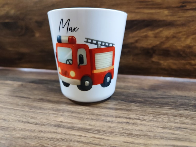 May include: White ceramic cup with a red fire truck illustration and the name "Max" printed on the front.