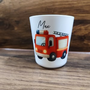 May include: White personalized cup with a red fire truck illustration and the name "Max" printed on the front.