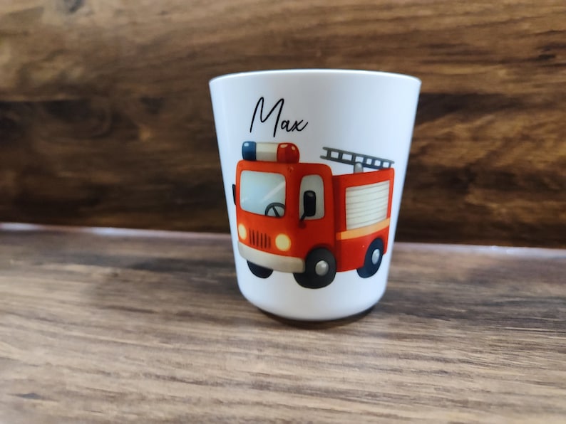 May include: White personalized cup with a red fire truck illustration and the name "Max" printed on the front.