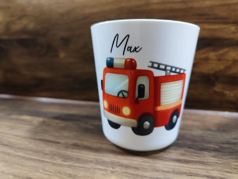 May include: White ceramic cup with a red fire truck illustration and the name "Max" written in black cursive.