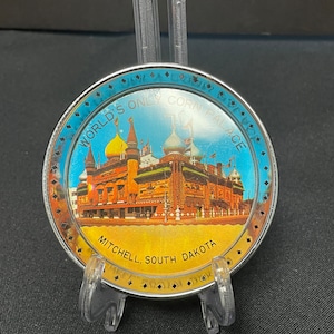 May include: A round souvenir featuring the World's Only Corn Palace in Mitchell, South Dakota. The image shows a colorful building with multiple domes and the text "World's Only Corn Palace" and "Mitchell, South Dakota". The border is blue.