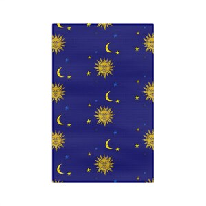 May include: A rectangular fabric featuring a deep blue background with a repeating pattern of yellow suns with faces, yellow crescent moons, and small blue and yellow stars scattered across the surface in a consistent celestial design.
