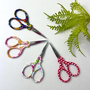 May include: Five pairs of small scissors with colorful patterned handles. The scissors have a floral, polka dot, and abstract design.