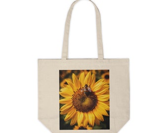 Peut inclure: Un sac fourre-tout avec un imprimé de tournesol et d'abeille. Le tournesol est jaune avec un centre brun et l'abeille est noire et jaune.