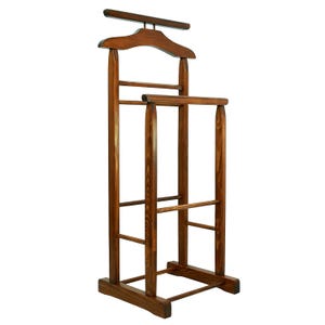 Puede incluir: Un perchero de madera con un colgador en la parte superior y un estante debajo. El perchero está hecho de madera marrón oscuro y tiene un diseño sencillo.