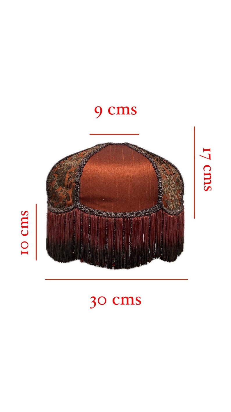 May include: A red lampshade with a gold and brown patterned fabric and a burgundy fringe trim. The lampshade measures 9 inches in diameter, 17 inches in height, and 30 inches in circumference.