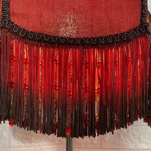 May include: A red lampshade with a black fringe and beaded accents.