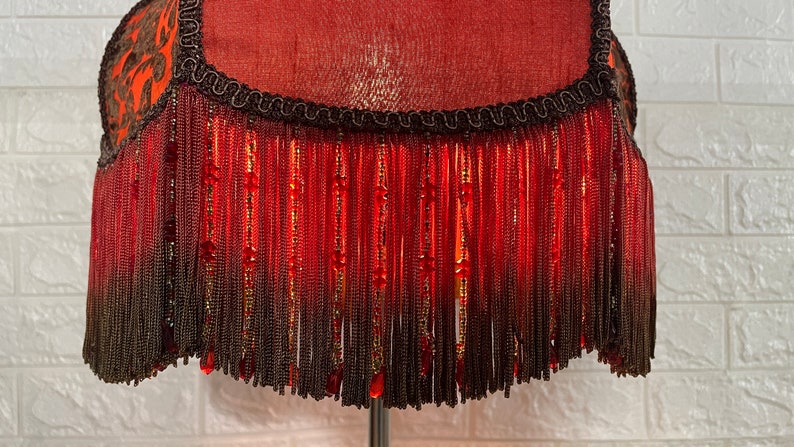 May include: A red lampshade with a black fringe and beaded accents.