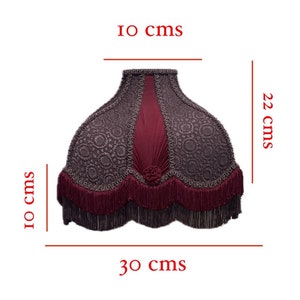 Puede incluir: Una pantalla de l&aacute;mpara de color burdeos y gris con ribete de flecos. La pantalla de la l&aacute;mpara tiene 22 cm de alto, 10 cm de ancho en la parte superior y 30 cm de ancho en la parte inferior.
