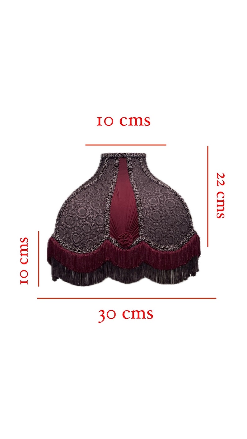 Puede incluir: Una pantalla de l&aacute;mpara de color burdeos y gris con ribete de flecos. La pantalla de la l&aacute;mpara tiene 22 cm de alto, 10 cm de ancho en la parte superior y 30 cm de ancho en la parte inferior.