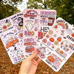Könnte beinhalten: Drei rosa und weiße Aufkleberbögen zum Thema Halloween mit verschiedenen Illustrationen und Texten. Die Bögen zeigen Kürbisse, Geister, Fledermäuse, Mais und die Texte "Spooky Babe", "True Crime", "In My Spooky Era", "Horror Movies and Chill", "Sweet & Spooky", "Let's Get Halloweird", "Cutest Pumpkin in the Patch", "The Boo Crew", "Scary Til I See Coffee".