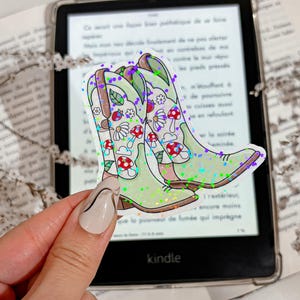 Op de afbeelding: Een paar groene cowboylaarzen met een bloemen- en paddenstoelontwerp. De laarzen zijn bedekt met glinsterende glitter.