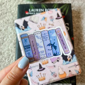 Könnte beinhalten: Ein Aufkleber mit fünf Fantasy-Buchcovern mit holografischem Glitzer. Die Titel lauten "Dragon Born Legend", "The Last Wyrm", "Dragon Kin", "Fire Wings II" und "Draconomicon".