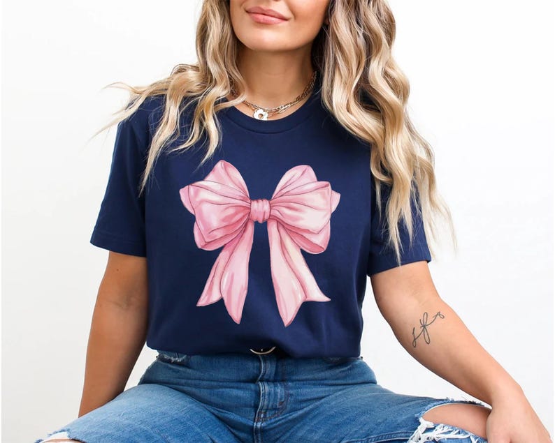 May include: A navy blue t-shirt with a pink bow graphic.