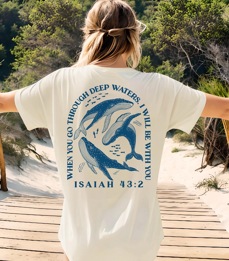 May include: White t-shirt with a blue graphic of whales swimming in a circle with the text "WHEN YOU GO THROUGH DEEP WATERS. I WILL BE WITH YOU ISAIAH 43:2"