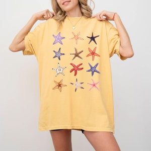 May include: A yellow oversized t-shirt with a colorful starfish pattern. The shirt has short sleeves and a relaxed fit.